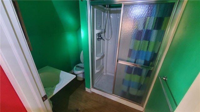 bathroom with a stall shower, wood finished floors, and toilet