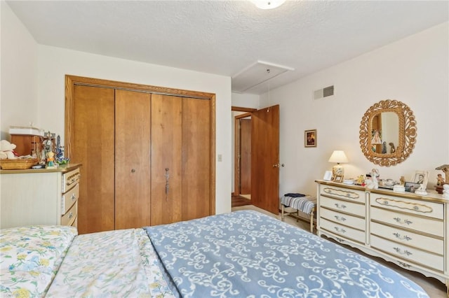 bedroom featuring attic access, a closet, and a textured ceiling