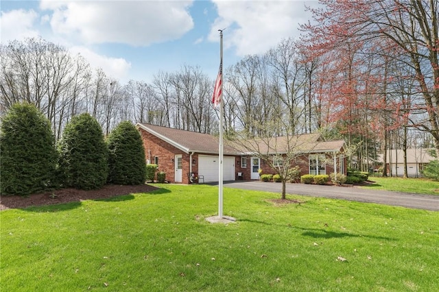 ranch-style house with brick siding, asphalt driveway, a garage, and a front yard