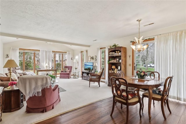 dining area featuring a chandelier, wood finished floors, and a textured ceiling