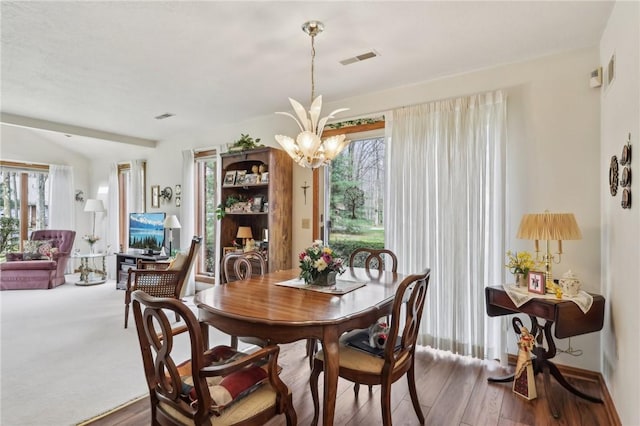 dining space with a chandelier, healthy amount of natural light, and wood finished floors