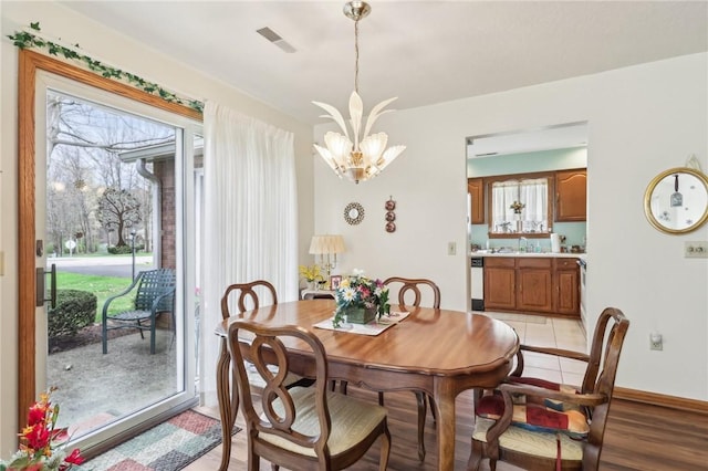dining room featuring a chandelier, plenty of natural light, baseboards, and light wood finished floors
