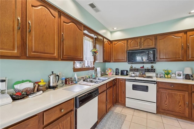 kitchen featuring white appliances, a sink, brown cabinets, light countertops, and recessed lighting