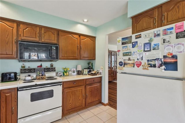 kitchen with white appliances, brown cabinetry, light countertops, and recessed lighting