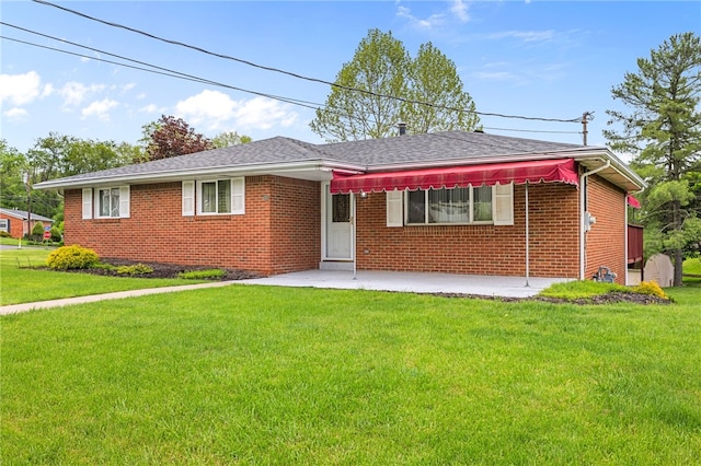 view of front of house featuring a patio area, a front lawn, and brick siding