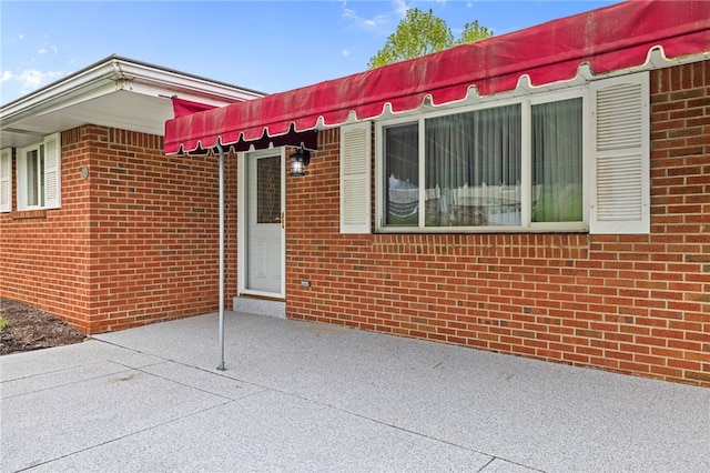 exterior space featuring brick siding and a patio