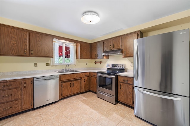 kitchen featuring stainless steel appliances, a sink, under cabinet range hood, and light countertops