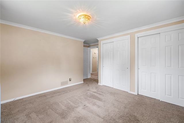 unfurnished bedroom featuring multiple closets, crown molding, carpet flooring, and baseboards