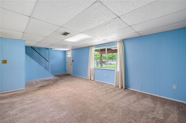 basement featuring carpet, stairway, a paneled ceiling, and baseboards