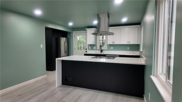 7709 Mark Dr, Penn Hills, PA 15147 - kitchen with freestanding refrigerator, island exhaust hood, a peninsula, light countertops, and light wood-style floors