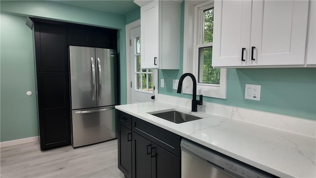 7709 Mark Dr, Penn Hills, PA 15147 - kitchen featuring stainless steel appliances, a sink, light stone countertops, white cabinetry, and light wood finished floors
