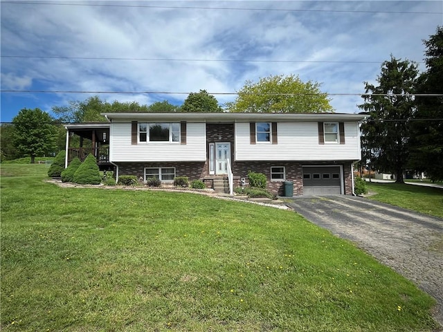 raised ranch featuring asphalt driveway, a garage, brick siding, and a front yard