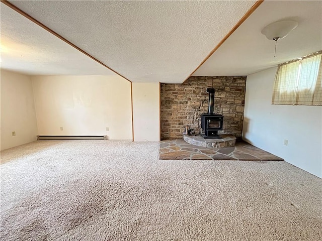 unfurnished living room featuring a baseboard heating unit, carpet floors, a wood stove, and a textured ceiling