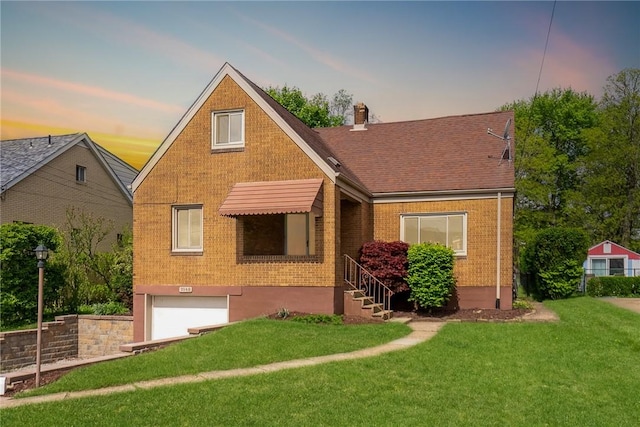 view of front of house with a garage, brick siding, and a yard