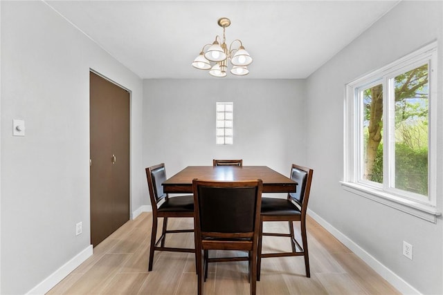 dining room with a chandelier, baseboards, and light wood-type flooring