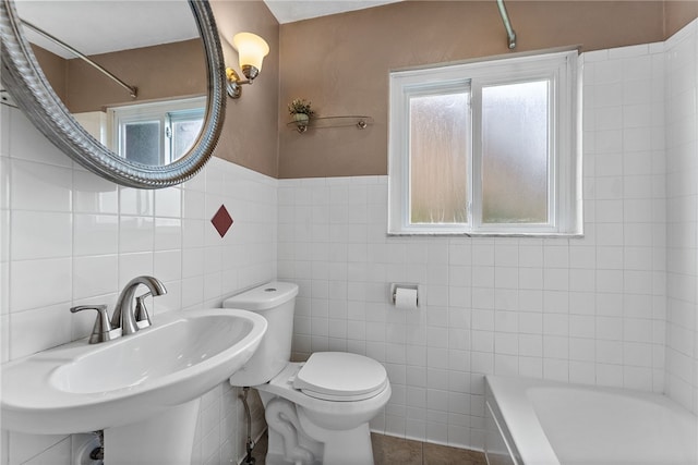 full bath with tile walls, healthy amount of natural light, toilet, a sink, and shower / bathtub combination