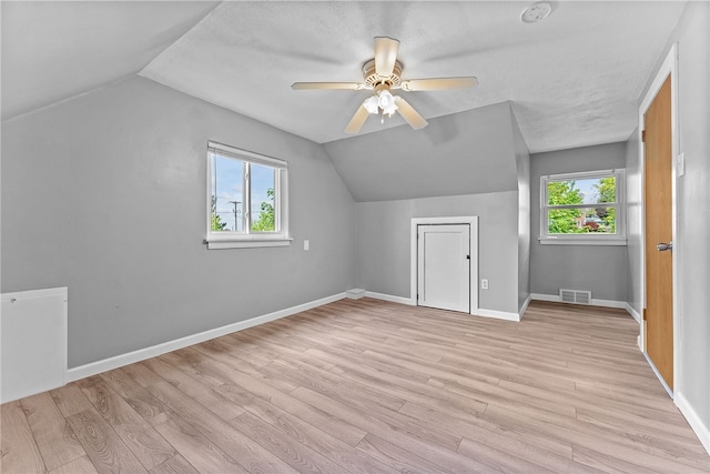 additional living space with lofted ceiling, a ceiling fan, light wood-type flooring, and baseboards