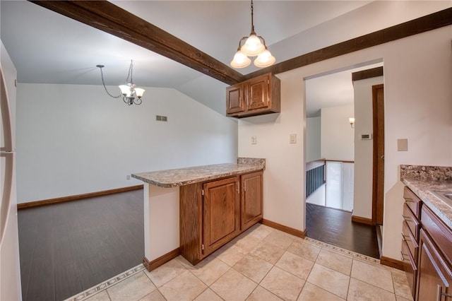 kitchen with brown cabinets, a chandelier, a peninsula, decorative light fixtures, and baseboards