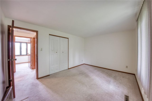 unfurnished bedroom featuring light colored carpet, baseboards, and a closet
