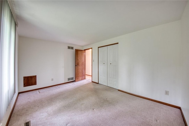 unfurnished bedroom featuring light colored carpet, a closet, and baseboards