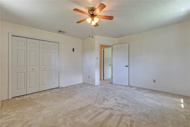 unfurnished bedroom with light colored carpet, a closet, and a ceiling fan
