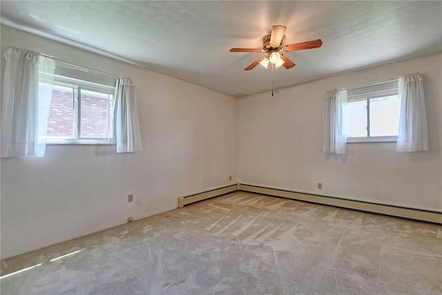 carpeted spare room featuring healthy amount of natural light, a ceiling fan, and a baseboard heating unit