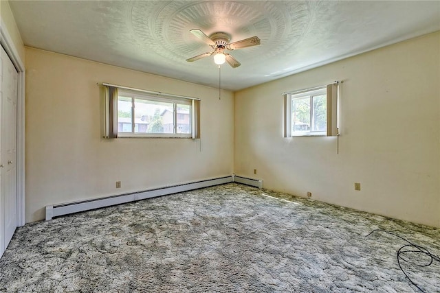 unfurnished bedroom featuring a baseboard heating unit, multiple windows, carpet floors, and ceiling fan