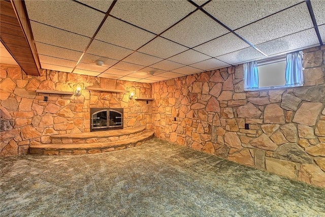 below grade area with carpet floors, a drop ceiling, and a fireplace