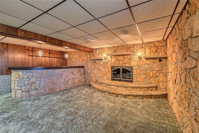 finished below grade area featuring a stone fireplace, carpet, and a paneled ceiling