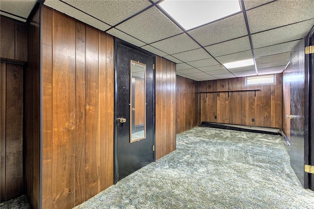 basement featuring carpet floors, wood walls, a wall mounted AC, and a drop ceiling