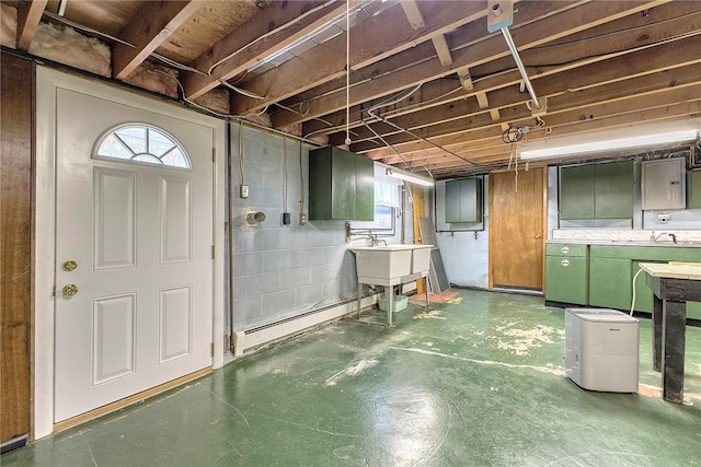 below grade area featuring a baseboard radiator, healthy amount of natural light, and a sink