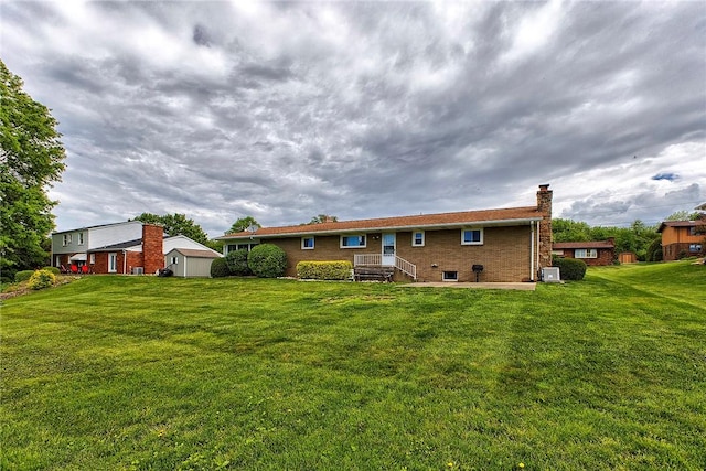 back of house with a chimney, brick siding, and a yard