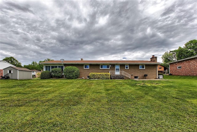 back of property with a chimney, a lawn, and brick siding