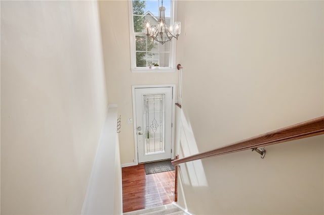entrance foyer featuring a chandelier, wood finished floors, healthy amount of natural light, and baseboards