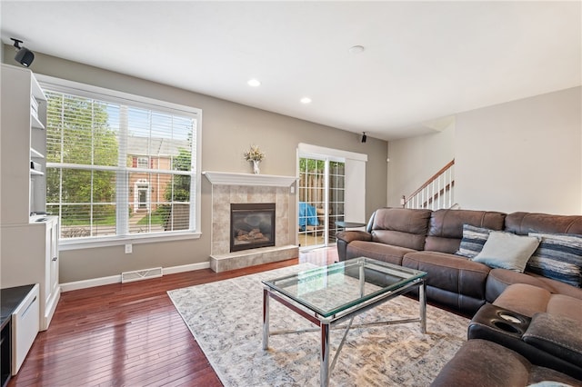 living area featuring dark wood finished floors, baseboards, a high end fireplace, recessed lighting, and stairway