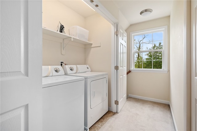 clothes washing area featuring separate washer and dryer, light carpet, and baseboards