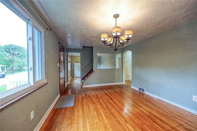 140 8th Ave, Ross Twp, PA 15229 - unfurnished dining area featuring a chandelier, wood finished floors, baseboards, a textured ceiling, and arched walkways