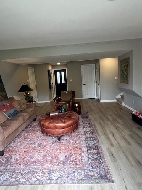living area featuring wood finished floors, baseboards, and stairway