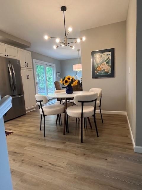 dining room with a chandelier, light wood-type flooring, and baseboards