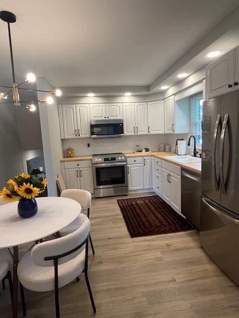 kitchen with appliances with stainless steel finishes, a sink, white cabinetry, light countertops, and recessed lighting