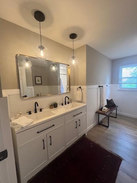 bathroom with wainscoting, wood finished floors, and double vanity