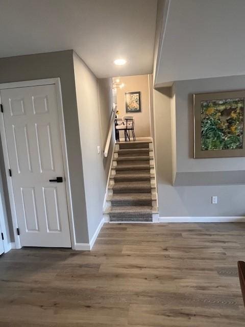 staircase with baseboards, wood finished floors, and recessed lighting