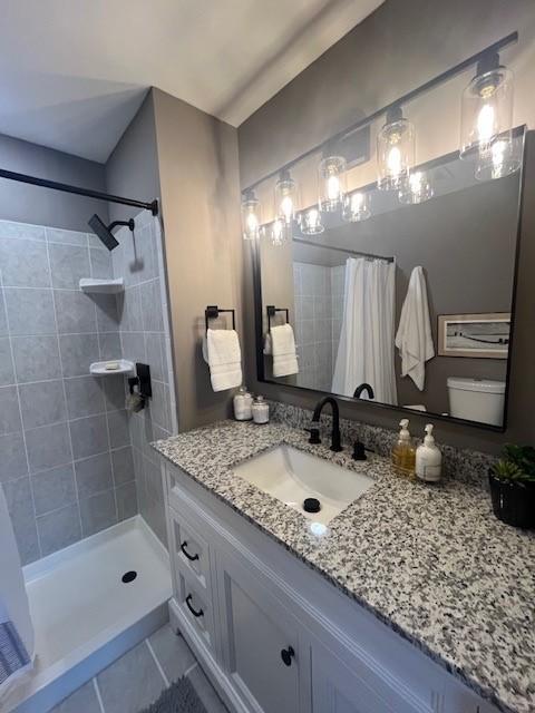 bathroom featuring tiled shower, tile patterned floors, and vanity