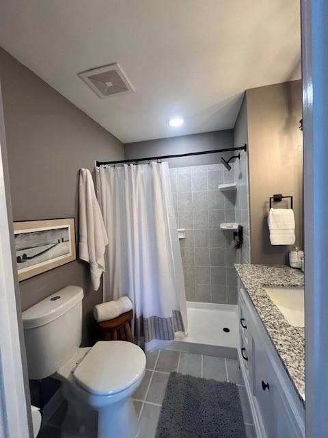 bathroom with toilet, tiled shower, tile patterned flooring, and vanity
