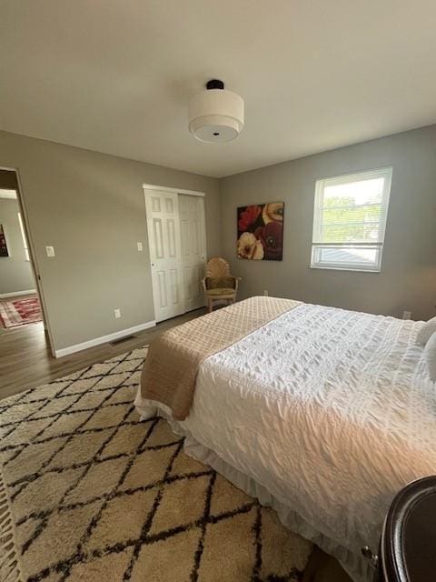 bedroom featuring wood finished floors, baseboards, and a closet