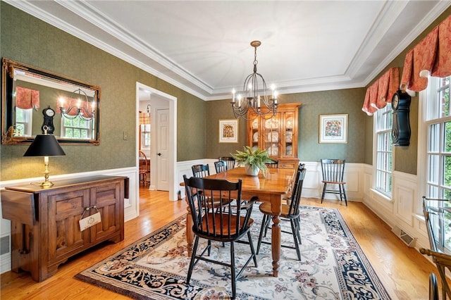 dining room featuring a chandelier, light wood-style flooring, wainscoting, and ornamental molding