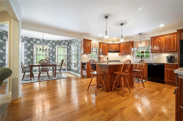 kitchen featuring black dishwasher, wallpapered walls, light wood-style floors, a kitchen breakfast bar, and a chandelier
