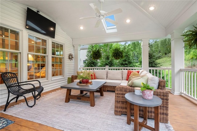 sunroom featuring vaulted ceiling, a ceiling fan, an outdoor living space, and a skylight