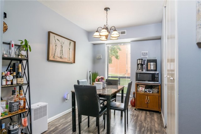 dining area featuring a chandelier, dark wood-type flooring, and baseboards