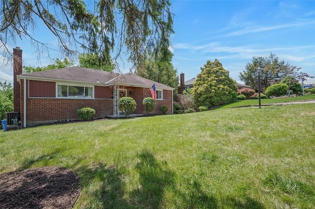 ranch-style home featuring a chimney, brick siding, a front lawn, and central AC